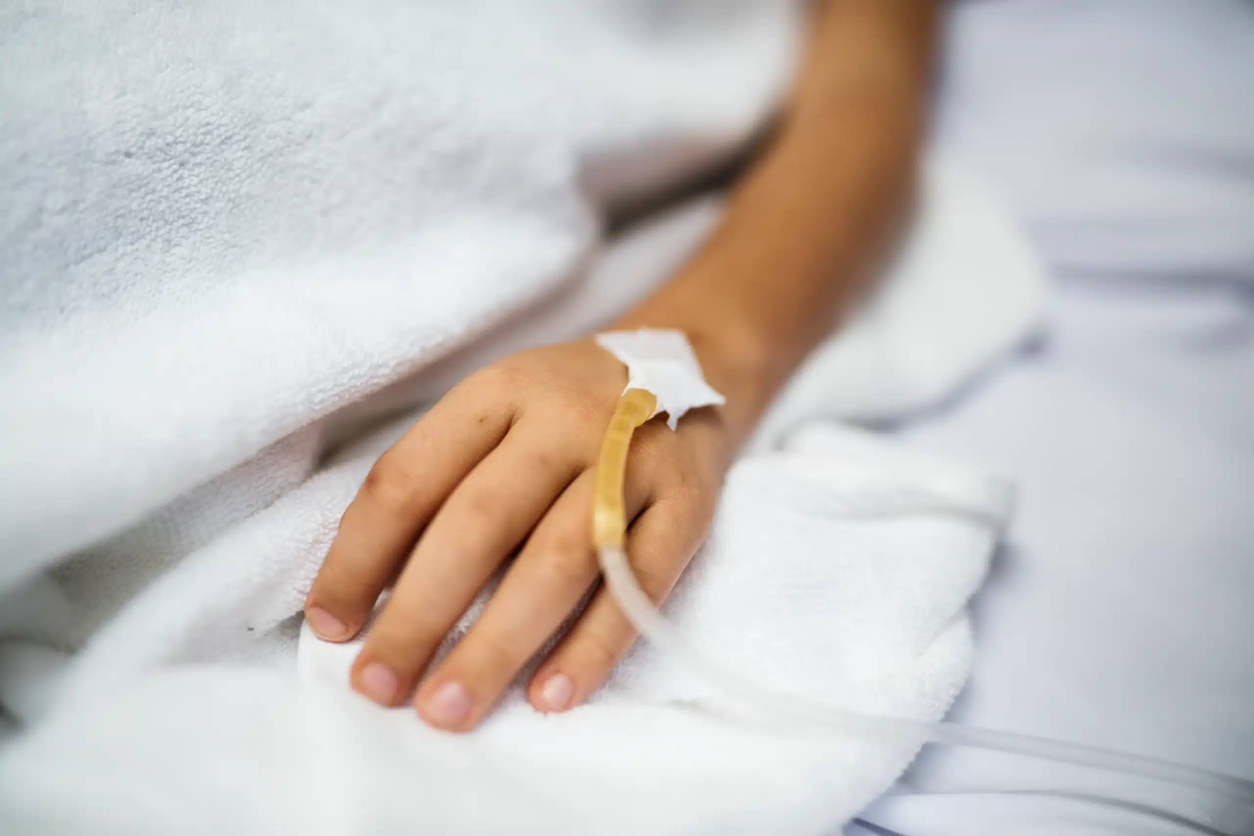 Hand with an IV line resting on a bed during a mobile IV drip at home in Bali